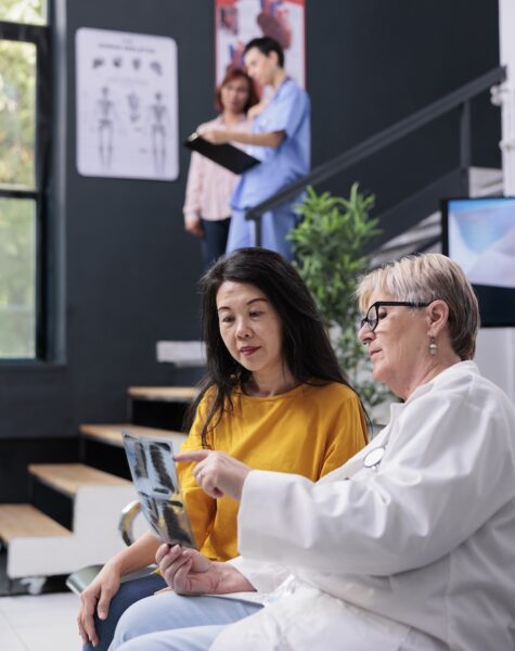 Diverse people looking at bones radiography scan Diverse people looking at bones radiography scan to find medical diagnosis, doctor explaining x ray exam results. Patient attending orthopedic examination with medic in waiting area at clinic.
