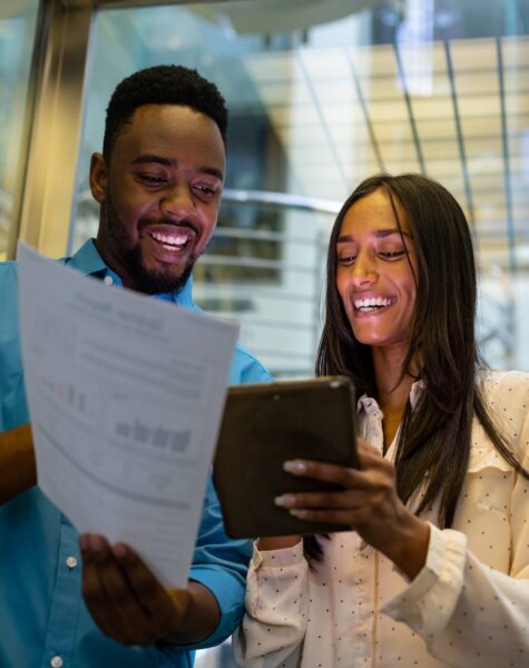 Happy multiracial colleagues discussing over document and tablet pc in elevator at modern workplace. unaltered, technology, business, teamwork and modern office concept. Happy multiracial colleagues discussing over document and tablet pc in elevator at modern workplace. unaltered, technology, business, teamwork and modern office concept.