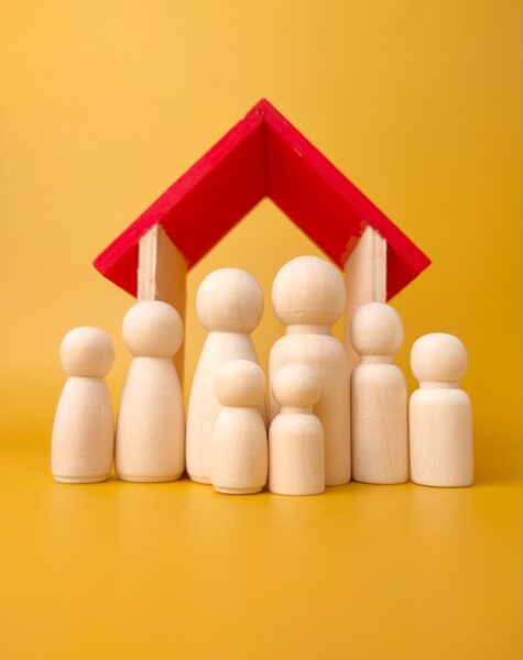 Wooden figures big family infront wooden house on a yellow background. Wooden figures big family infront wooden house on a yellow background.